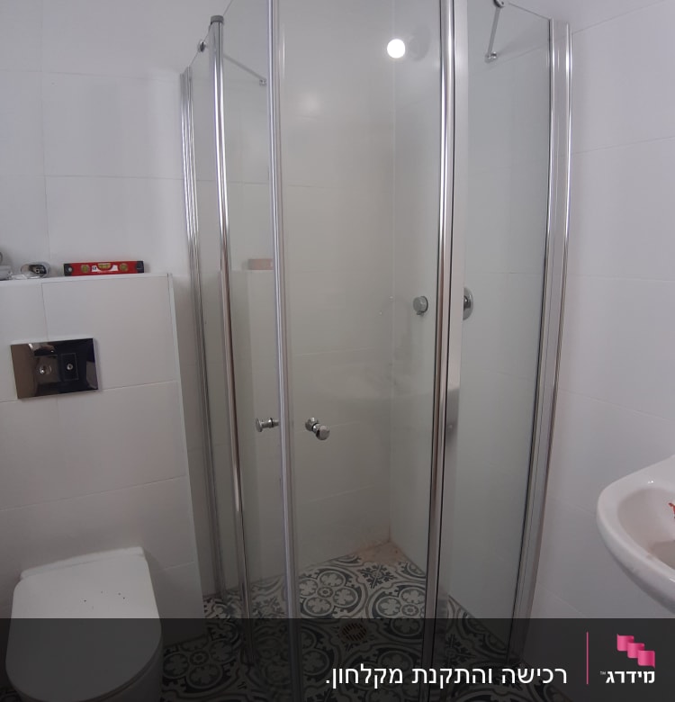 מקלחון זכוכית עם דלתות מתכת בחדר אמבטיה